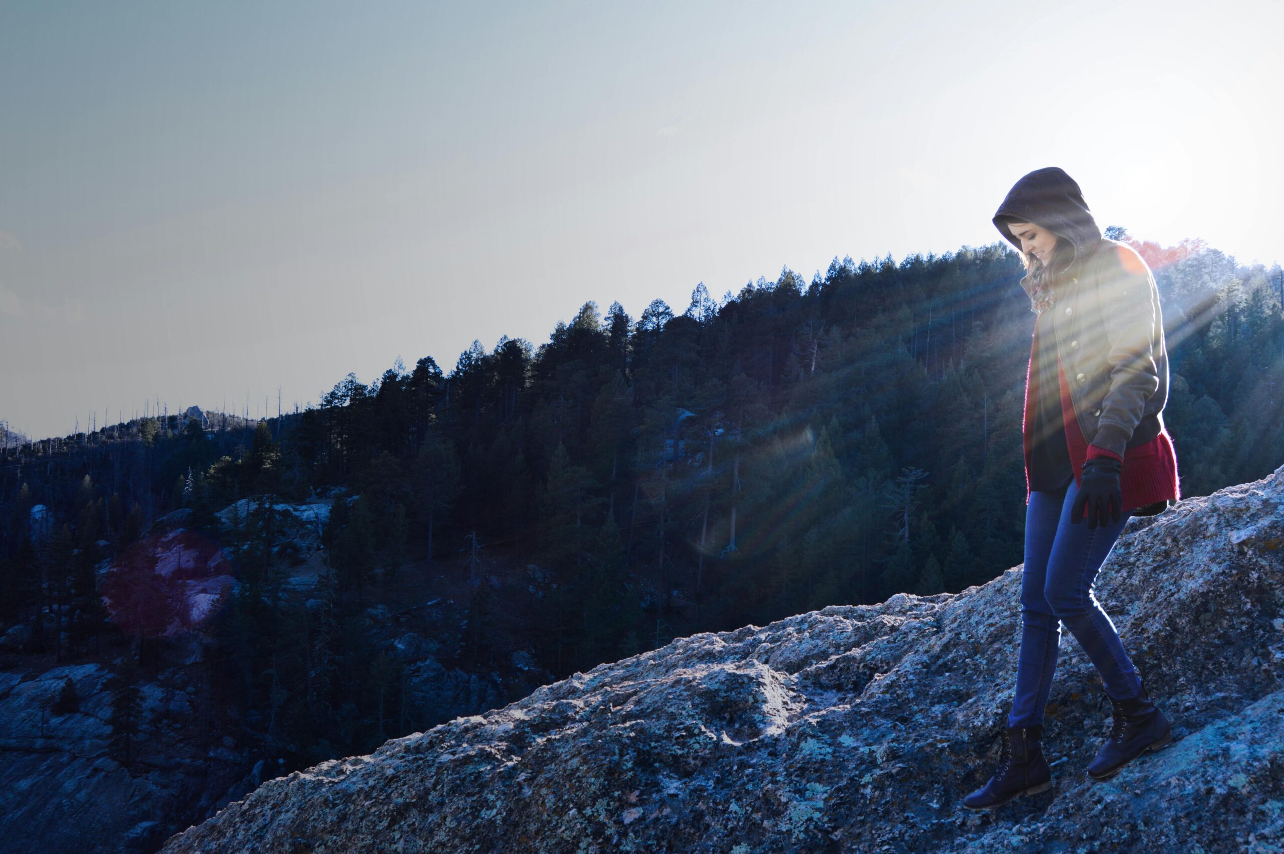 Person hiking on rocky terrain at Mount Lemmon during sunrise with scenic forest view.