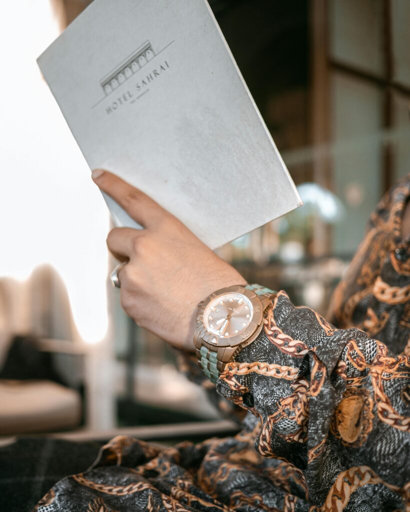 Close-up of an elegant hand holding a brochure at Hotel Sahrai, featuring a stylish wristwatch.